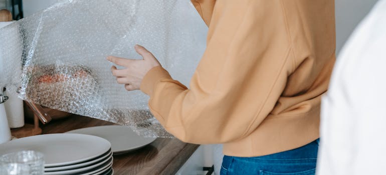 A person packing fragile items for the move, something to do after you choose the perfect Ontario city to relocate to.