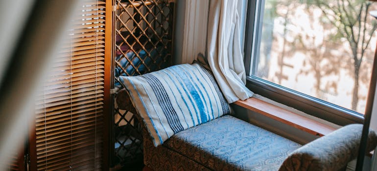 Small chair with a throw pillow next to the window.
