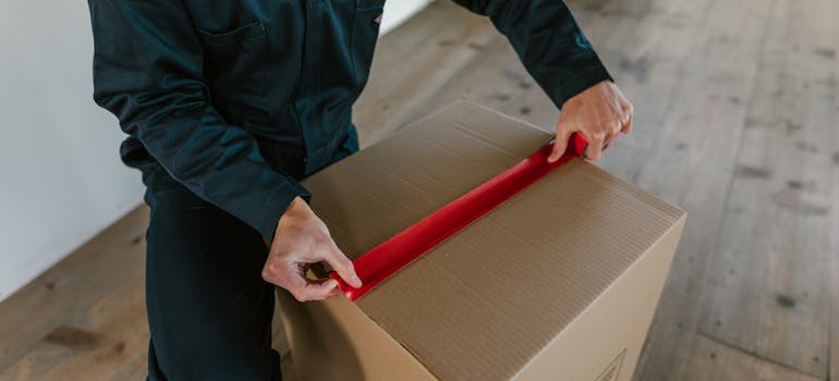 A professional mover closing a moving box.