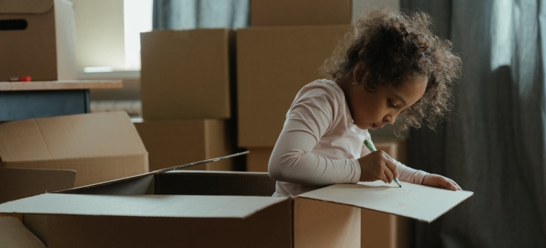 A child drawing on a moving box.