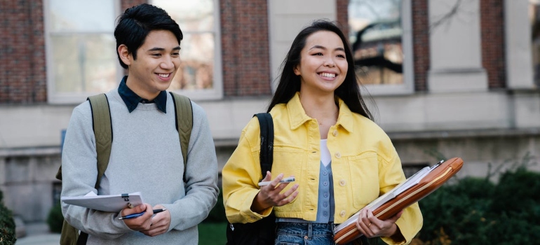 Teenagers smiling while holding papers.