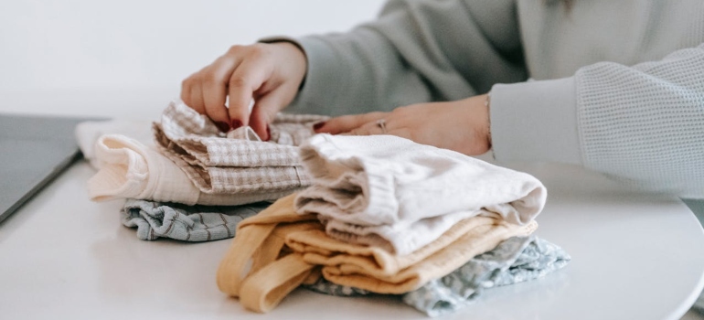 A woman using packing techniques to preserve sentimental baby items in storage.