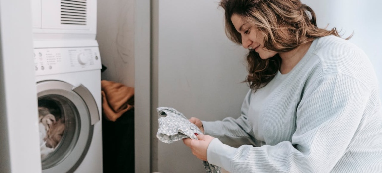 A woman washing baby clothes to preserve sentimental baby items in storage.