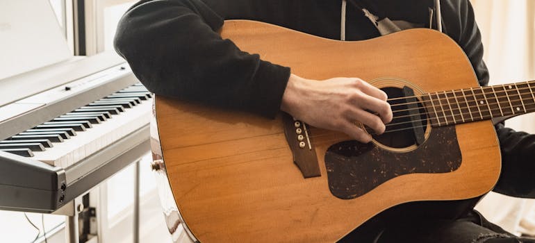 A man playing the guitar after moving music gear in Ontario.