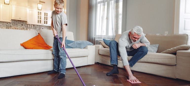 A father and son cleaning the living room floor.