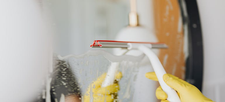 A person cleaning a mirror after decluttering before an international move out of Ontario.