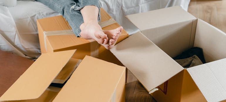 A person relaxing while packing moving boxes.